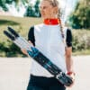 Woman holding a pair of FF rollerskis outdoors.