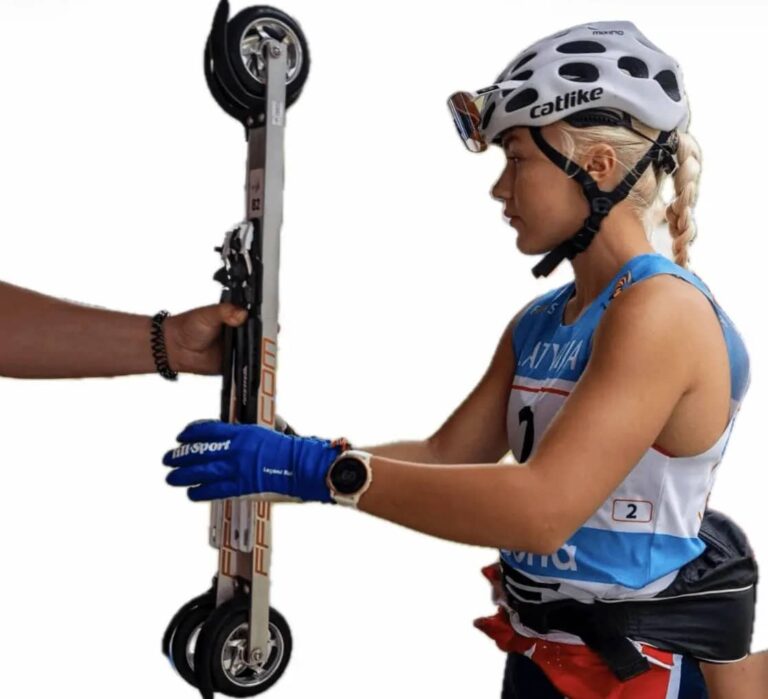 Emilie Lia examining FF Rollerskis equipment wearing a white helmet and blue training top.